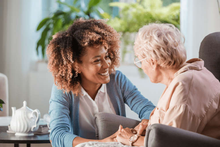 A caregiver sharing a warm conversation with an older woman at home